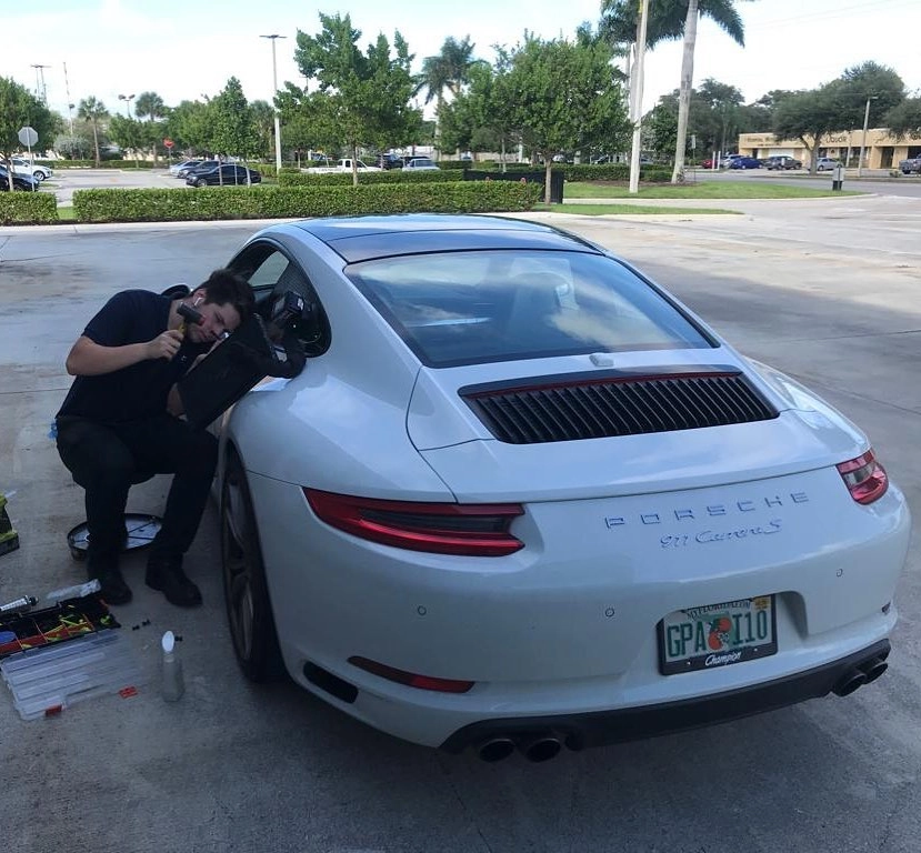 Brandon repairing a dent on a white Porsche